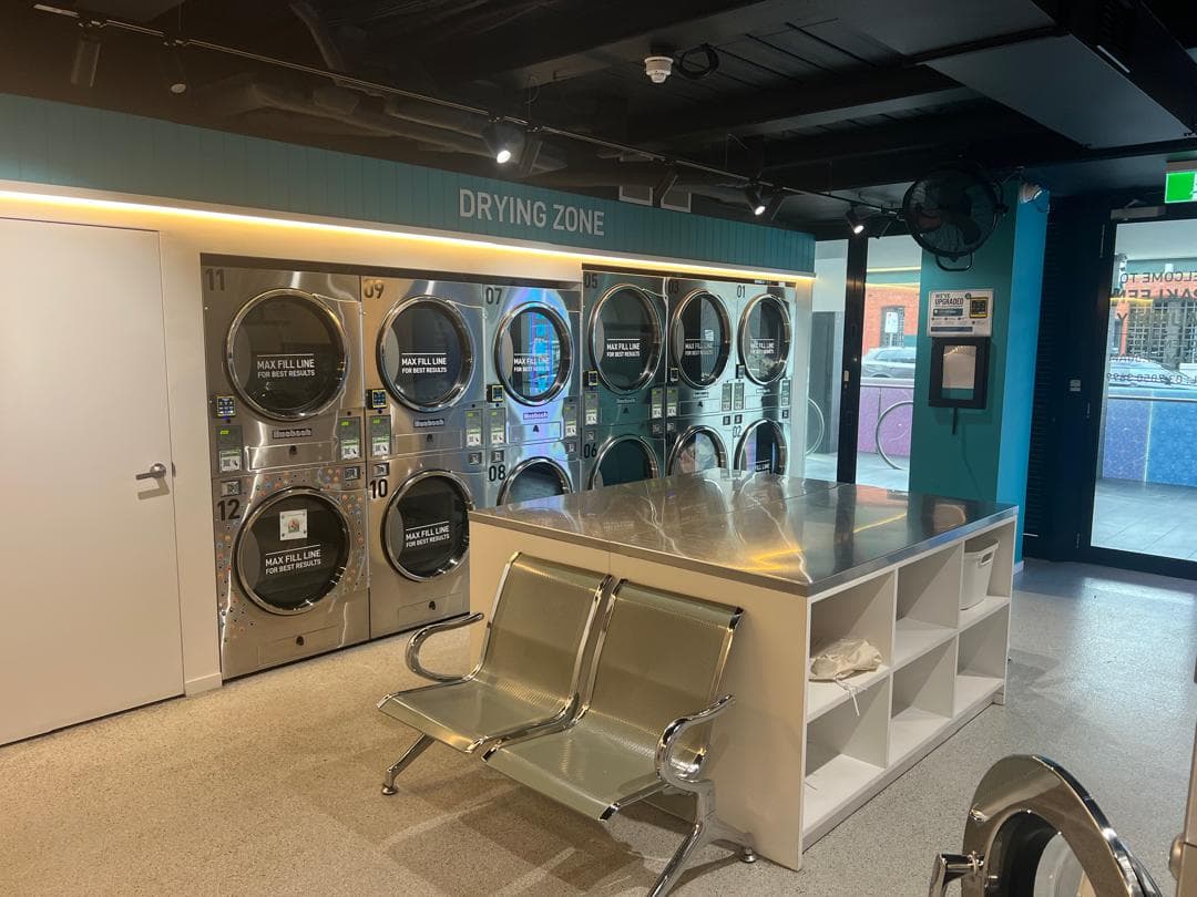 Seating and folding area beside the drying zone at the Spakleen St Kilda laundromat