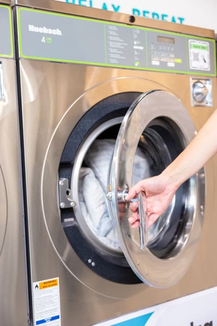 Hand opening the door of a Spakleen washing machine