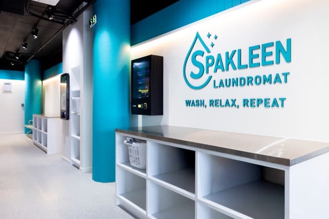 Folding benches and the cashless payment kiosk beneath the Spakleen Laundromat wall sign at Werribee