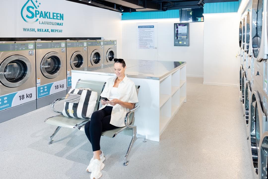 Customer seated beside a row of 18kg Spakleen washers with stacked dryers opposite