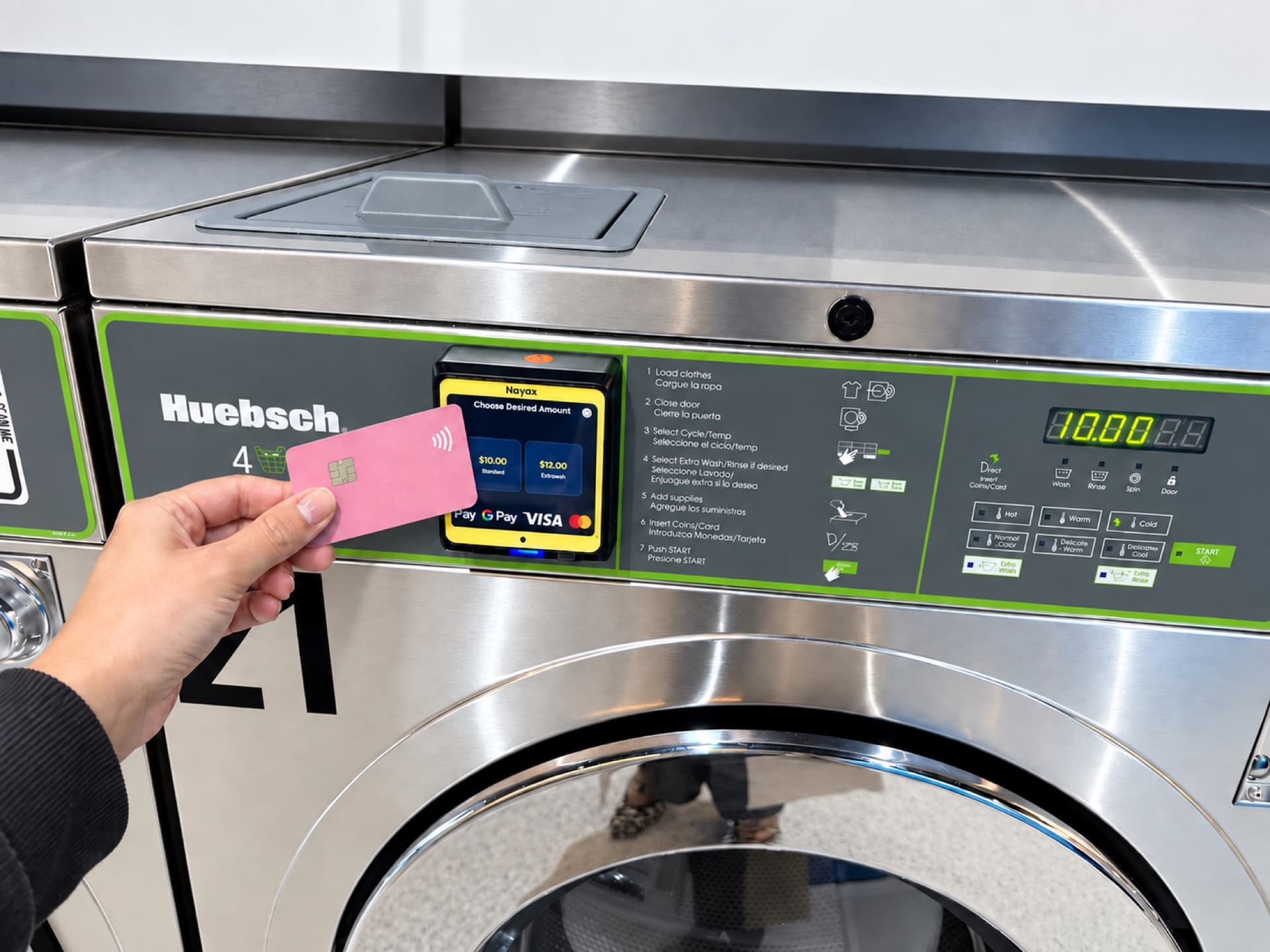 Customer holding a bank card to the contactless Nayax reader on a Spakleen washing machine to start a cycle without coins, with Apple Pay, Google Pay and Visa accepted on screen