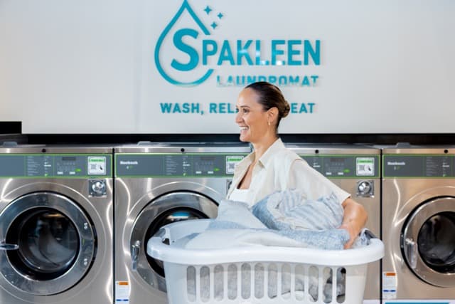 Customer loading a basket of bedding into a large-capacity Spakleen washing machine